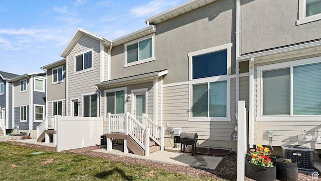back of house with central AC unit and stucco siding