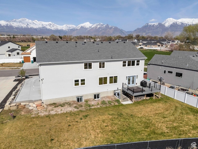 rear view of property with a deck with mountain view, a residential view, fence, and a lawn