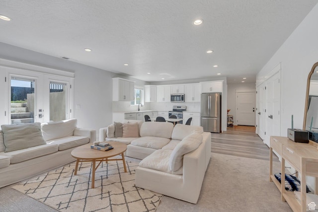 living area featuring a textured ceiling, light wood finished floors, and recessed lighting