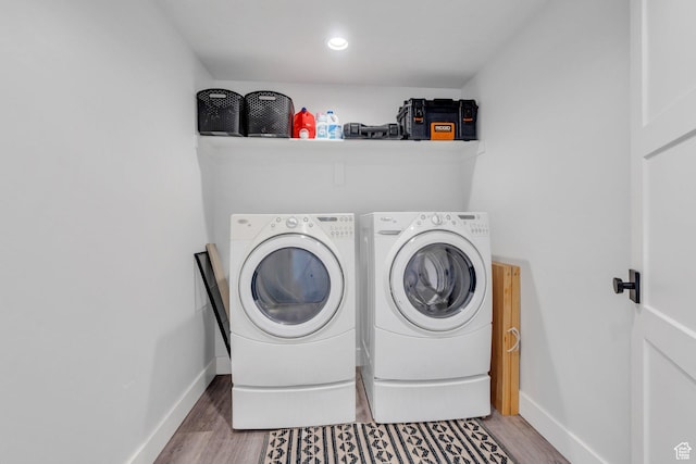 washroom with separate washer and dryer, laundry area, baseboards, and wood finished floors