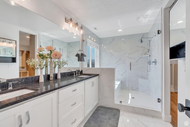 bathroom featuring a sink, a marble finish shower, marble finish floor, and a textured ceiling