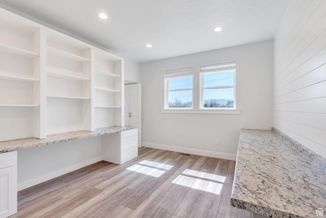 interior space featuring light wood-type flooring, baseboards, recessed lighting, built in study area, and a textured ceiling