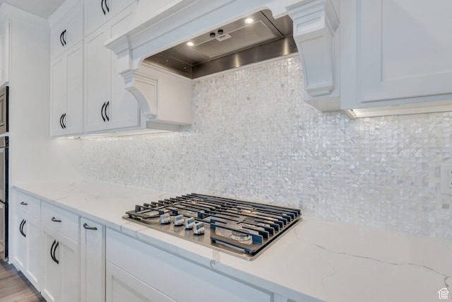 kitchen featuring white cabinets, custom exhaust hood, tasteful backsplash, and stainless steel gas stovetop