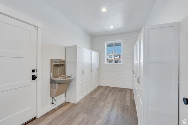 unfurnished bedroom featuring recessed lighting, wooden walls, light wood-style floors, and a textured ceiling