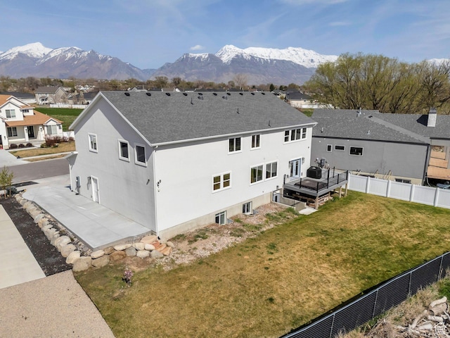 exterior space featuring central air condition unit, a mountain view, a lawn, fence, and a shingled roof
