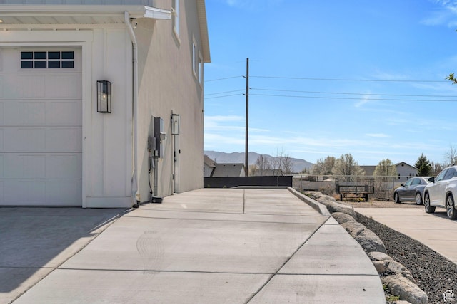 view of home's exterior with concrete driveway, a mountain view, fence, and a garage