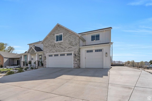 traditional-style home featuring board and batten siding, driveway, stone siding, and a garage