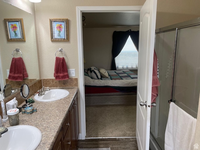 ensuite bathroom with wood finished floors, a sink, a shower stall, and connected bathroom