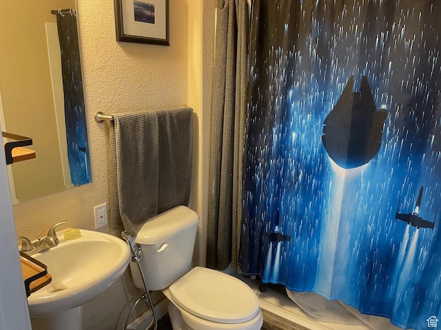 full bath with a textured wall, curtained shower, a sink, and toilet