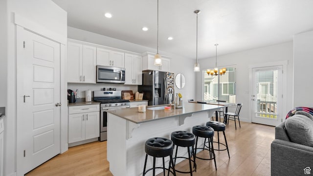 kitchen featuring light wood-style floors, white cabinets, appliances with stainless steel finishes, and a breakfast bar area
