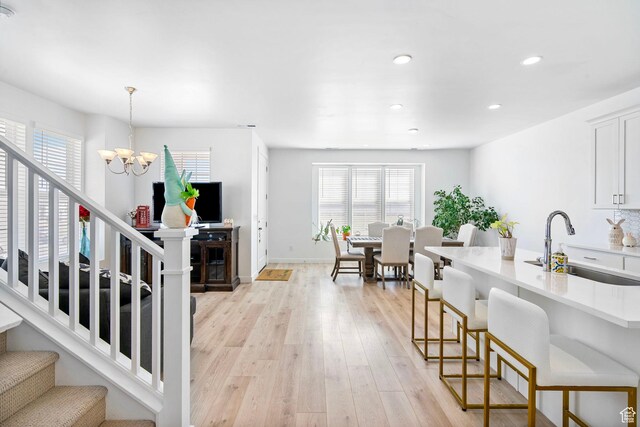 11612 S Watercourse Rd W, South Jordan, UT 84009 - kitchen with light wood-style flooring, a sink, a wealth of natural light, and a notable chandelier