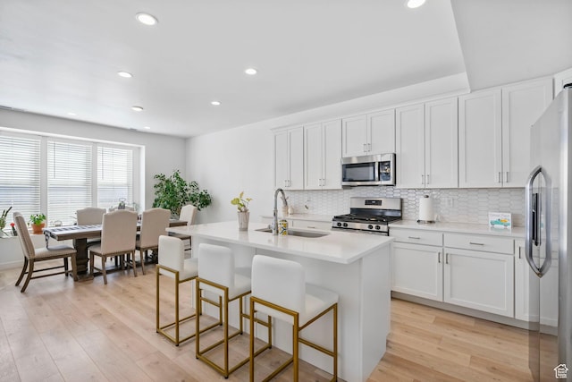 11612 S Watercourse Rd W, South Jordan, UT 84009 - kitchen with light wood-style flooring, a sink, white cabinetry, stainless steel appliances, and decorative backsplash