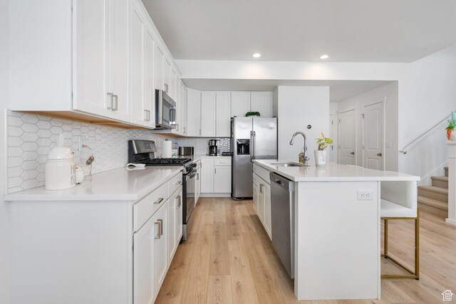 11612 S Watercourse Rd W, South Jordan, UT 84009 - kitchen with stainless steel appliances, light wood-style flooring, a kitchen bar, and a sink