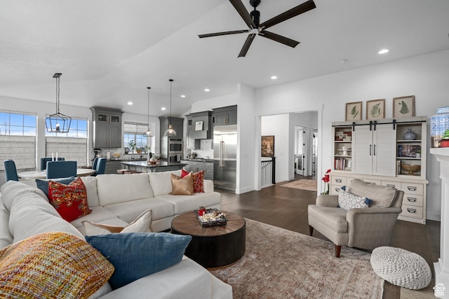 living room featuring recessed lighting, a ceiling fan, a barn door, dark wood-type flooring, and lofted ceiling