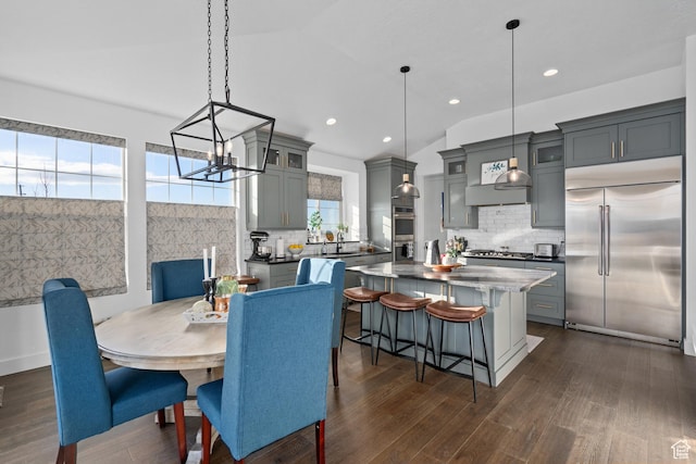dining space with dark wood-style flooring, recessed lighting, an inviting chandelier, and lofted ceiling