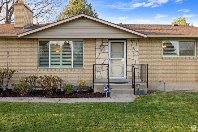 3168 W Ryan Dr, Taylorsville, UT 84129 - view of front of house featuring a front yard, brick siding, a chimney, and a shingled roof