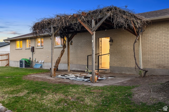 3168 W Ryan Dr, Taylorsville, UT 84129 - back of property at dusk featuring brick siding, a yard, central AC unit, and a shingled roof