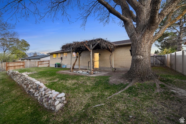 3168 W Ryan Dr, Taylorsville, UT 84129 - rear view of property featuring brick siding, a fenced backyard, and a lawn