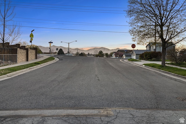 3168 W Ryan Dr, Taylorsville, UT 84129 - view of road featuring street lighting, a mountain view, traffic signs, curbs, and sidewalks