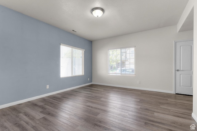 empty room featuring visible vents, baseboards, and wood finished floors