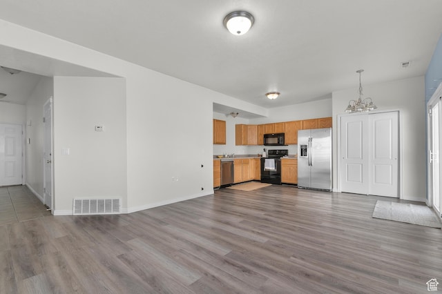 kitchen featuring visible vents, black appliances, wood finished floors, light countertops, and baseboards