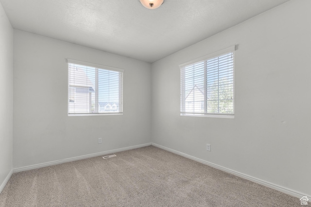 spare room featuring visible vents, baseboards, a textured ceiling, and carpet floors