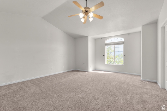 carpeted spare room with ceiling fan, baseboards, and lofted ceiling