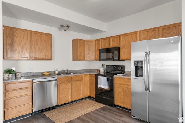 kitchen featuring dark wood-style floors, a sink, and black appliances