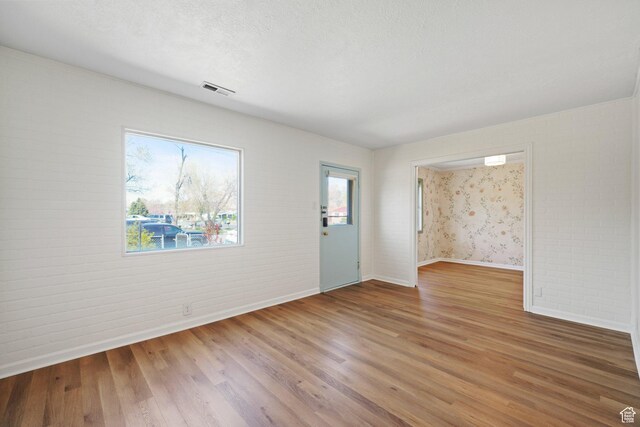 1489 W 300 S, Salt Lake City, UT 84104 - spare room featuring a textured ceiling, visible vents, wood finished floors, brick wall, and baseboards