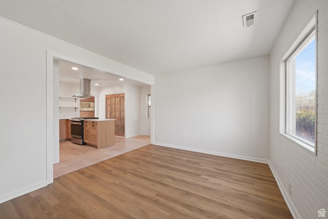 1489 W 300 S, Salt Lake City, UT 84104 - unfurnished living room featuring light wood-style flooring, brick wall, baseboards, and visible vents