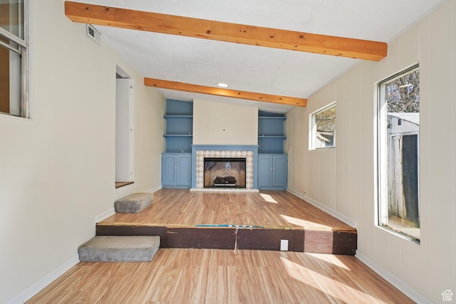 1489 W 300 S, Salt Lake City, UT 84104 - unfurnished living room featuring visible vents, baseboards, a fireplace with raised hearth, beamed ceiling, and wood finished floors