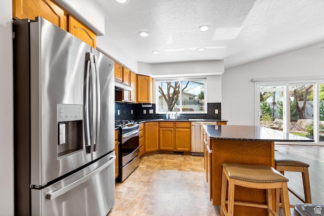 1181 W 4550 S Unit 26, Riverdale, UT 84405 - kitchen featuring stainless steel appliances, under cabinet range hood, backsplash, a center island, and a kitchen breakfast bar