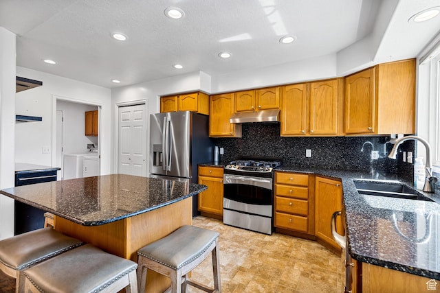 1181 W 4550 S Unit 26, Riverdale, UT 84405 - kitchen featuring stainless steel appliances, independent washer and dryer, a sink, brown cabinets, and backsplash
