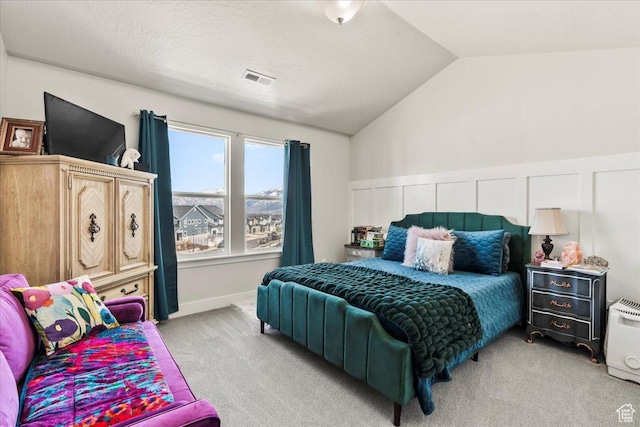 bedroom with visible vents, light colored carpet, vaulted ceiling, and a textured ceiling