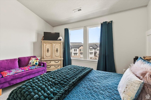 bedroom with a textured ceiling, lofted ceiling, and visible vents