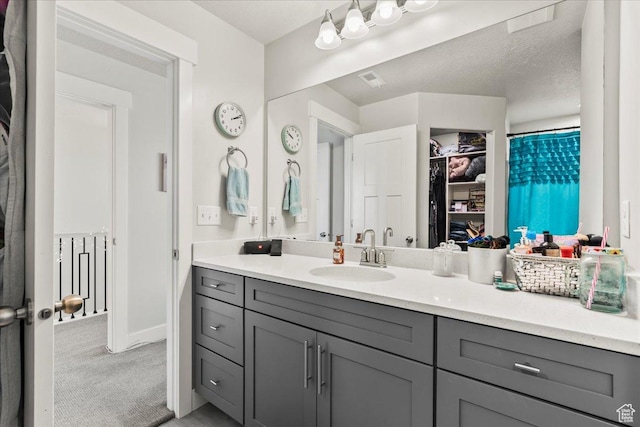 full bath featuring a walk in closet, vanity, baseboards, and visible vents