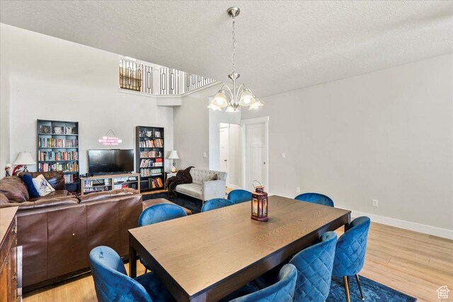 dining area with a chandelier, light wood-style floors, baseboards, and a textured ceiling