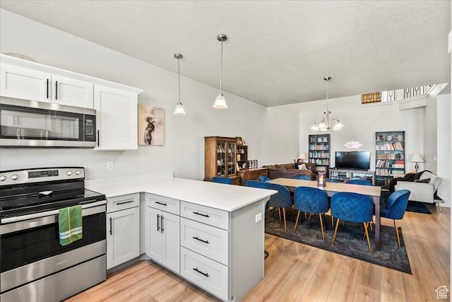 kitchen featuring stainless steel appliances, open floor plan, light countertops, and a peninsula