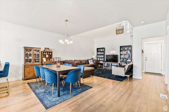 dining room with visible vents, a notable chandelier, light wood-style floors, and a textured ceiling