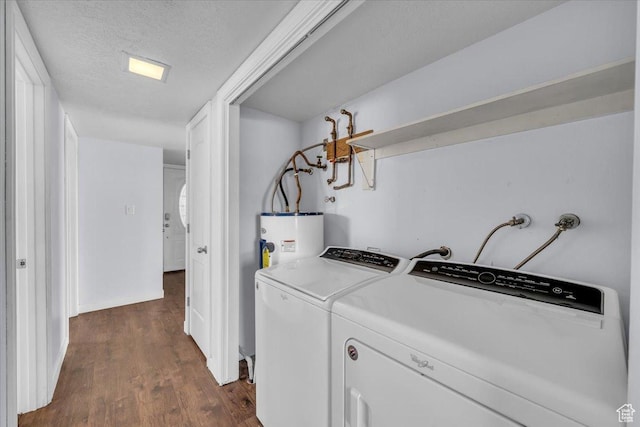 laundry area featuring water heater, washing machine and clothes dryer, a textured ceiling, and dark wood-style floors