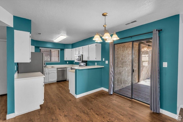 kitchen featuring a notable chandelier, a peninsula, white cabinetry, light countertops, and stainless steel appliances