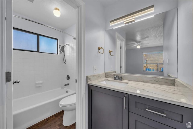 bathroom with vanity, bathing tub / shower combination, a ceiling fan, toilet, and wood finished floors