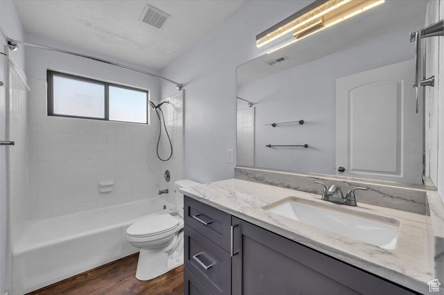 full bath featuring wood finished floors, vanity, bathtub / shower combination, and visible vents