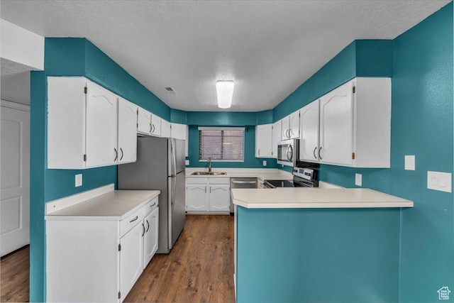 kitchen with a textured ceiling, white cabinetry, appliances with stainless steel finishes, dark wood-style flooring, and a sink