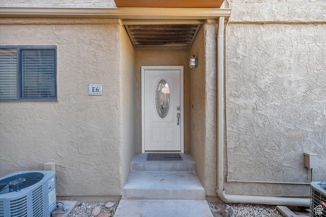 property entrance with central AC and stucco siding
