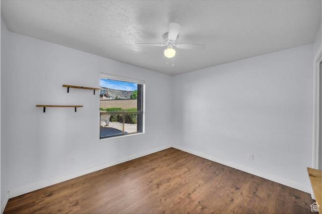spare room with baseboards, a ceiling fan, wood finished floors, and a textured ceiling
