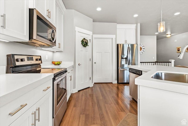 249 N 590 E, Vineyard, UT 84059 - kitchen featuring light countertops, appliances with stainless steel finishes, white cabinetry, wood finished floors, and pendant lighting
