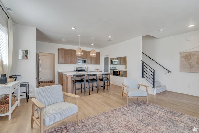 929 S 950 W, American Fork, UT 84003 - kitchen featuring brown cabinetry, light wood-style flooring, an island with sink, and stainless steel appliances