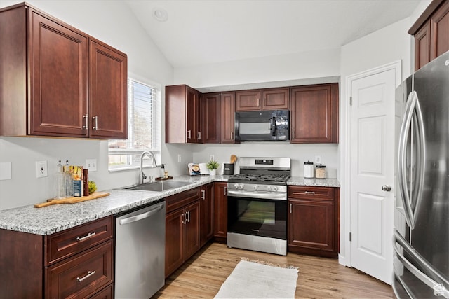 2124 N 2525 W, Clinton, UT 84015 - kitchen featuring light wood-type flooring, vaulted ceiling, appliances with stainless steel finishes, light stone counters, and a sink