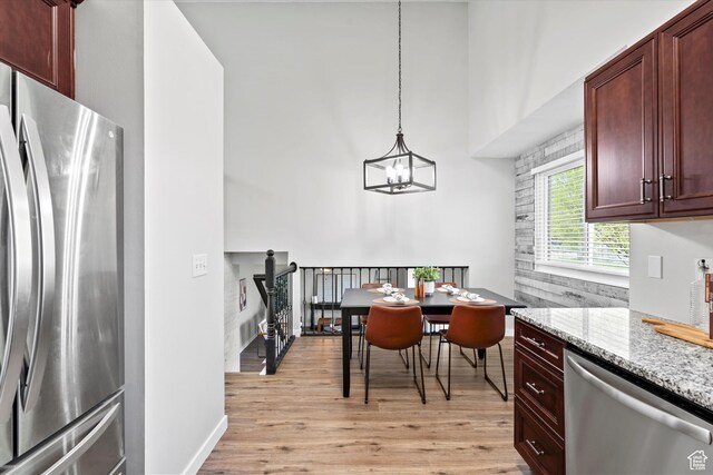 2124 N 2525 W, Clinton, UT 84015 - dining room featuring light wood-style floors, a high ceiling, an inviting chandelier, and baseboards